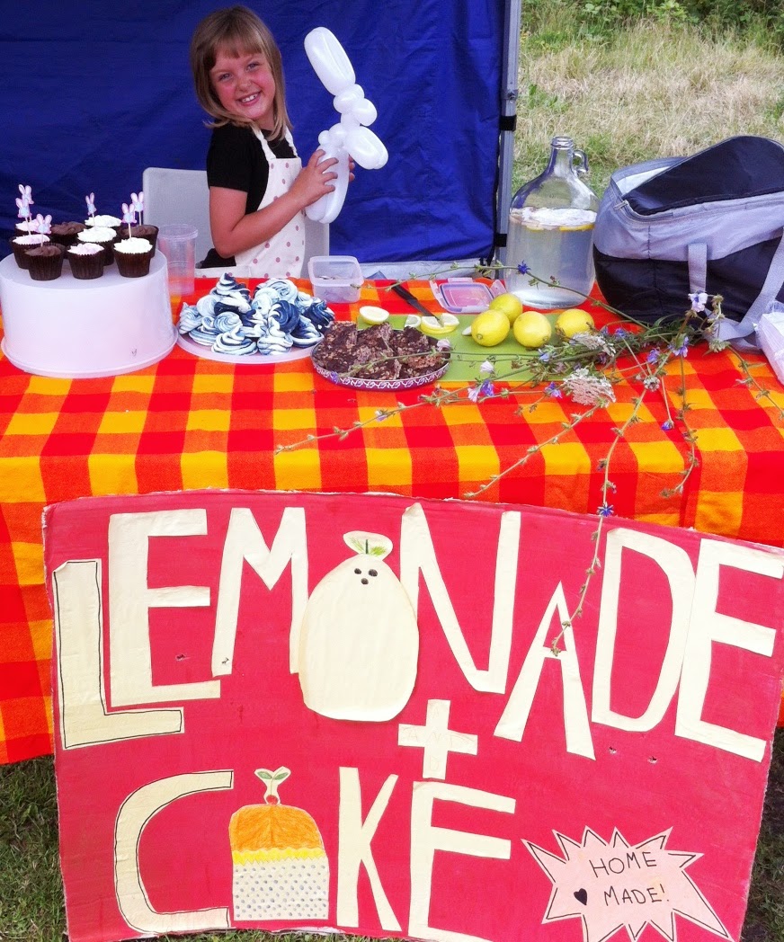 Lulu smiling from behind her lemonade stall in the park