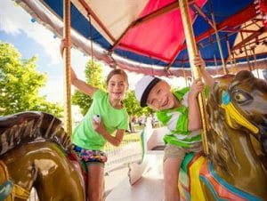 Two children smiling on the merry go round fair attraction